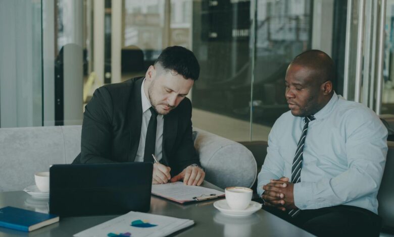 Two businessmen signing a document at a table.